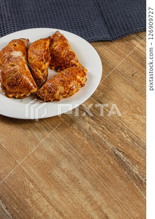 Pumpkin-filled pastries resting on a white plate on wooden table 126909727