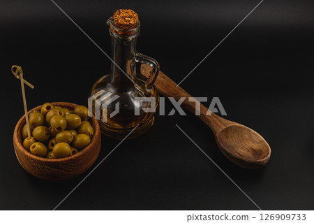 Olives and oil on dark background with wooden spoon and bowl Olives and oil on dark background with wooden spoon and bowl 126909733