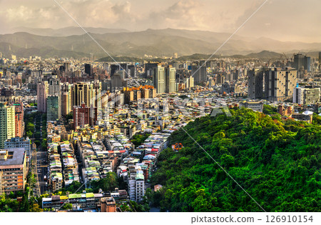 Seen from the lush crest of Xiangshan Mountain, Taipei, Taiwan, the metropolis fans out across its basin in tight rows of low rooftops and clusters of modern high-rise towers, while the forested slope Seen from the lush crest of Xiangshan Mountain, Taipei, Taiwan, the metropolis fans out across its basin in tight rows of low rooftops and clusters of modern high-rise towers, while the forested slope 126910154