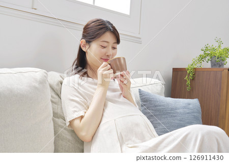 Pregnant woman drinking decaffeinated coffee at home Pregnant woman drinking decaffeinated coffee at home 126911430