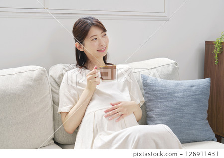Pregnant woman drinking decaffeinated coffee at home Pregnant woman drinking decaffeinated coffee at home 126911431