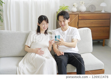 Pregnant wife and husband using smartphones in the living room 126911478