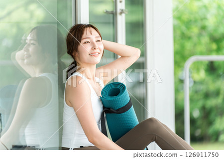 一個帶著瑜珈墊的瑜珈教練的女人，一個做瑜珈和普拉提的女人 126911750