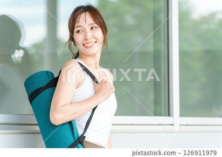 Healthy woman holding a yoga mat (yoga instructor/yogini) 126911979