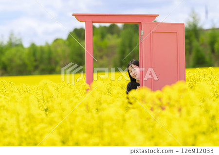 A woman sightseeing in a rapeseed field in full bloom (pink door) 126912033