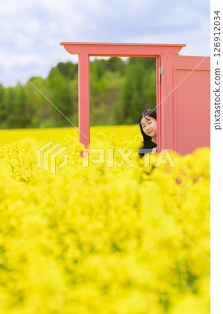 一名女子在盛開的油菜花田裡觀光（粉紅色門） 126912034