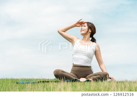 A woman meditating, doing yoga, stretching and pilates in the grassland (healthcare and diet) A woman meditating, doing yoga, stretching and pilates in the grassland (healthcare and diet) 126912516
