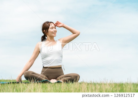 A woman meditating, doing yoga, stretching and pilates in the grassland (healthcare and diet) A woman meditating, doing yoga, stretching and pilates in the grassland (healthcare and diet) 126912517