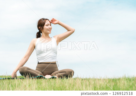 A woman meditating, doing yoga, stretching and pilates in the grassland (healthcare and diet) A woman meditating, doing yoga, stretching and pilates in the grassland (healthcare and diet) 126912518