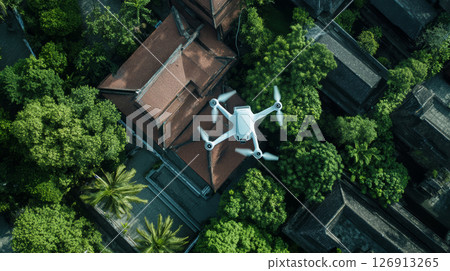 drone hovers above house surrounded by lush greenery, capturing detailed aerial views of landscape 126913265