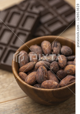 Cocoa beans and chocolate bar in a wooden bowl on a wooden table Cocoa beans and chocolate bar in a wooden bowl on a wooden table 126913619