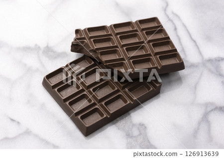 Cracked chocolate bar on a marble background Cracked chocolate bar on a marble background 126913639