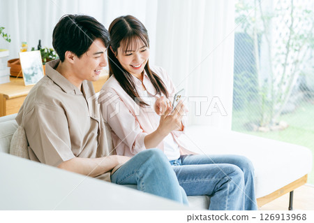 夫婦在客廳裡看智能手機 夫婦在客廳裡看智能手機 126913968
