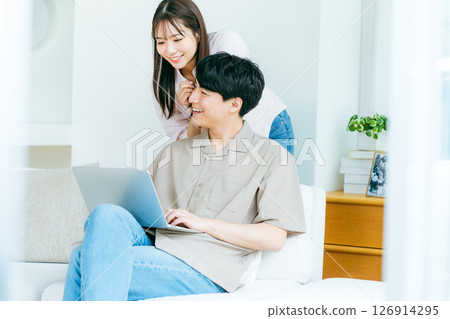A couple looking at a computer in the living room A couple looking at a computer in the living room 126914295