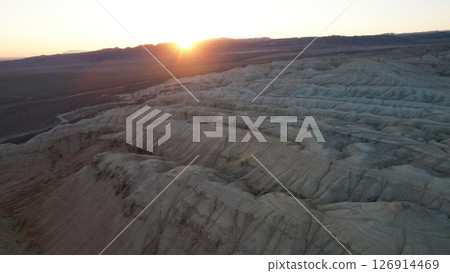 Sun setting behind mountain range in desert landscape Sun setting behind mountain range in desert landscape 126914469