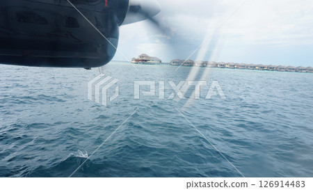 Seaplane flying over water bungalows in the maldives Seaplane flying over water bungalows in the maldives 126914483