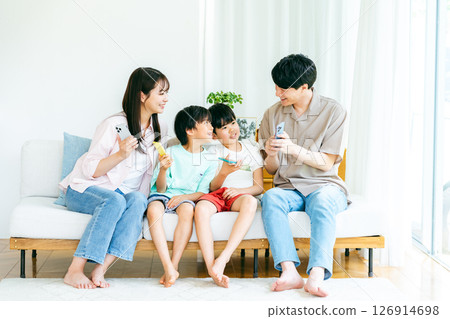 Family sitting on sofa with smartphone 126914698