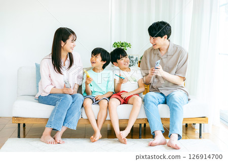 Family sitting on sofa with smartphone 126914700