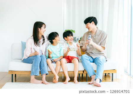 Family sitting on sofa with smartphone 126914701