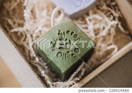 Close-up of green olive oil soap stamped with botanical design inside kraft packaging. Natural beauty products, clean cosmetics, plant-based skincare, herbal soap 126914980