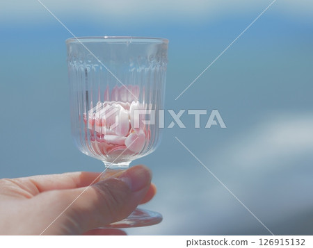 手拿著一個帶有粉紅色櫻桃殼的玻璃杯 126915132
