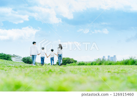 Family walking through a grassland with blue sky Family walking through a grassland with blue sky 126915460