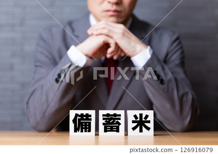 一位身著西裝的中年男性商人,手裡拿著一袋囤積的米 一位身著西裝的中年男性商人,手裡拿著一袋囤積的米 126916079