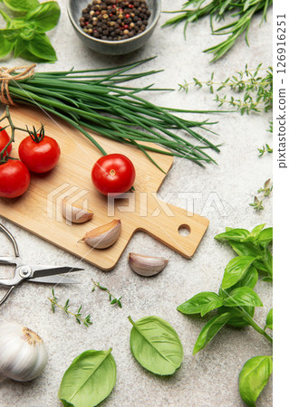 Fresh herbs, spices, tomatoes and garlic creating a frame on kitchen table Fresh herbs, spices, tomatoes and garlic creating a frame on kitchen table 126916251