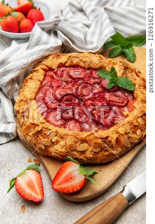 Delicious homemade strawberry galette decorated with almond petals and fresh mint 126916271