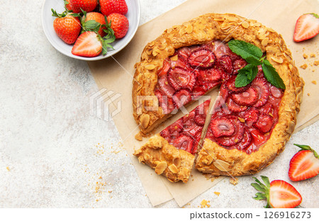 Delicious homemade strawberry galette with almond flakes and fresh mint on baking paper Delicious homemade strawberry galette with almond flakes and fresh mint on baking paper 126916273