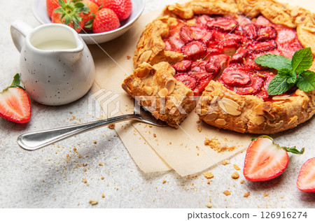 Delicious homemade strawberry galette with almond petals baking on parchment paper 126916274