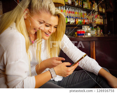 Girls in pub using smart phone 126916758