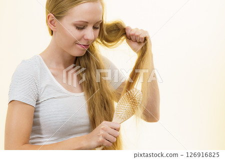 Blonde girl brushing her long hair Blonde girl brushing her long hair 126916825
