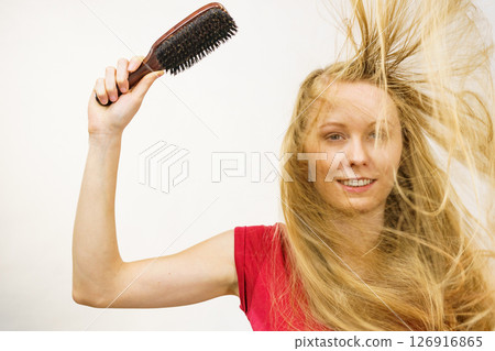 Blonde girl long blowing hair holds natural bristles brush 126916865