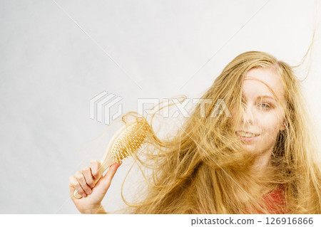 Blonde girl long tangled hair holds brush Blonde girl long tangled hair holds brush 126916866