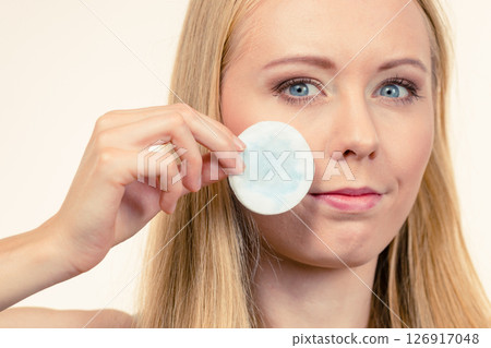 Woman cleaning her face skin with cotton pad Woman cleaning her face skin with cotton pad 126917048
