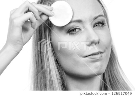Woman cleaning her face skin with cotton pad Woman cleaning her face skin with cotton pad 126917049