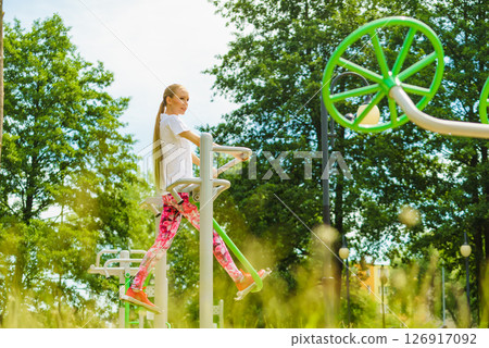 Woman doing exercise in outdoor gym Woman doing exercise in outdoor gym 126917092