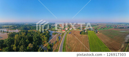 Panoramic aerial view of flooded areas near rural village, surrounded by green fields and farmlands. Countryside landscape Panoramic aerial view of flooded areas near rural village, surrounded by green fields and farmlands. Countryside landscape 126917303