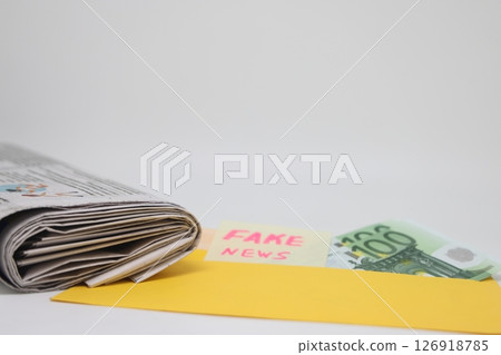 An envelope with money lies on a newspaper with fake news.  126918785