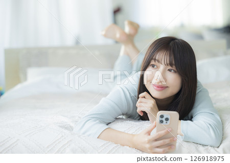 一名婦女在床上的看一個智能手機 126918975