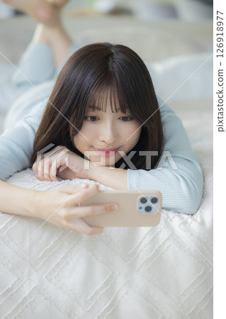 A woman watching a smartphone in bed 126918977