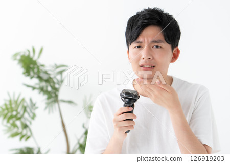 Man shaving his beard with a shaver Man shaving his beard with a shaver 126919203
