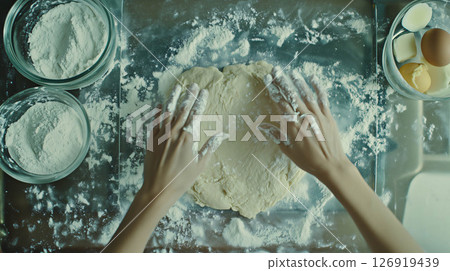 Baker kneading dough for bread making on floured surface 126919439