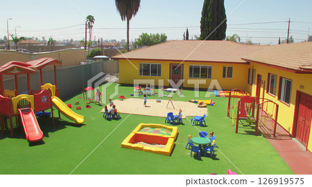 Children playing on colorful slides and swings in a sunny kindergarten playground 126919575