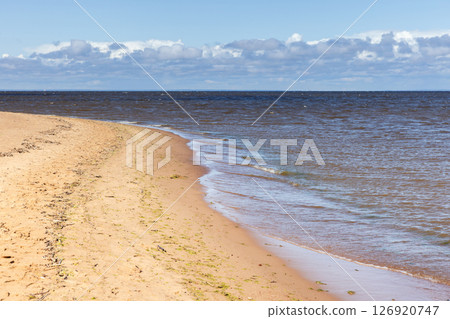 Calm sandy shoreline with soft waves lapping onto the coast Calm sandy shoreline with soft waves lapping onto the coast 126920747
