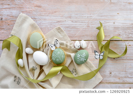 Stylish decorated easter eggs on linen cloth on a light wooden background. Top view. 126920925