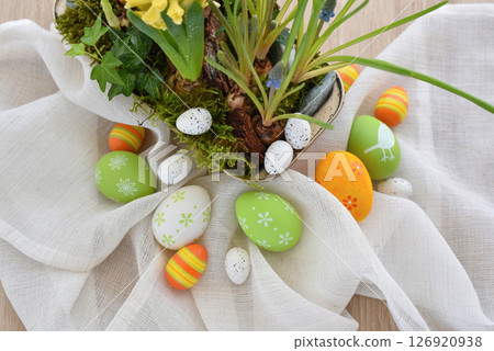Colorful easter eggs on linen cloth and spring primroses in a pot. Easter still life 126920938