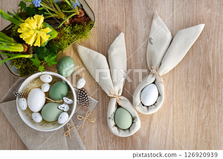 Easter eggs in a white bowl on linen cloth and spring primroses in a pot. Easter eggs in a white bowl on linen cloth and spring primroses in a pot. 126920939