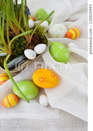 Colorful easter eggs on linen cloth and spring primroses in a pot. Easter still life 126920943